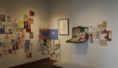 albert reyes art corner with various paintings, cards and open suitcase with paintings inside